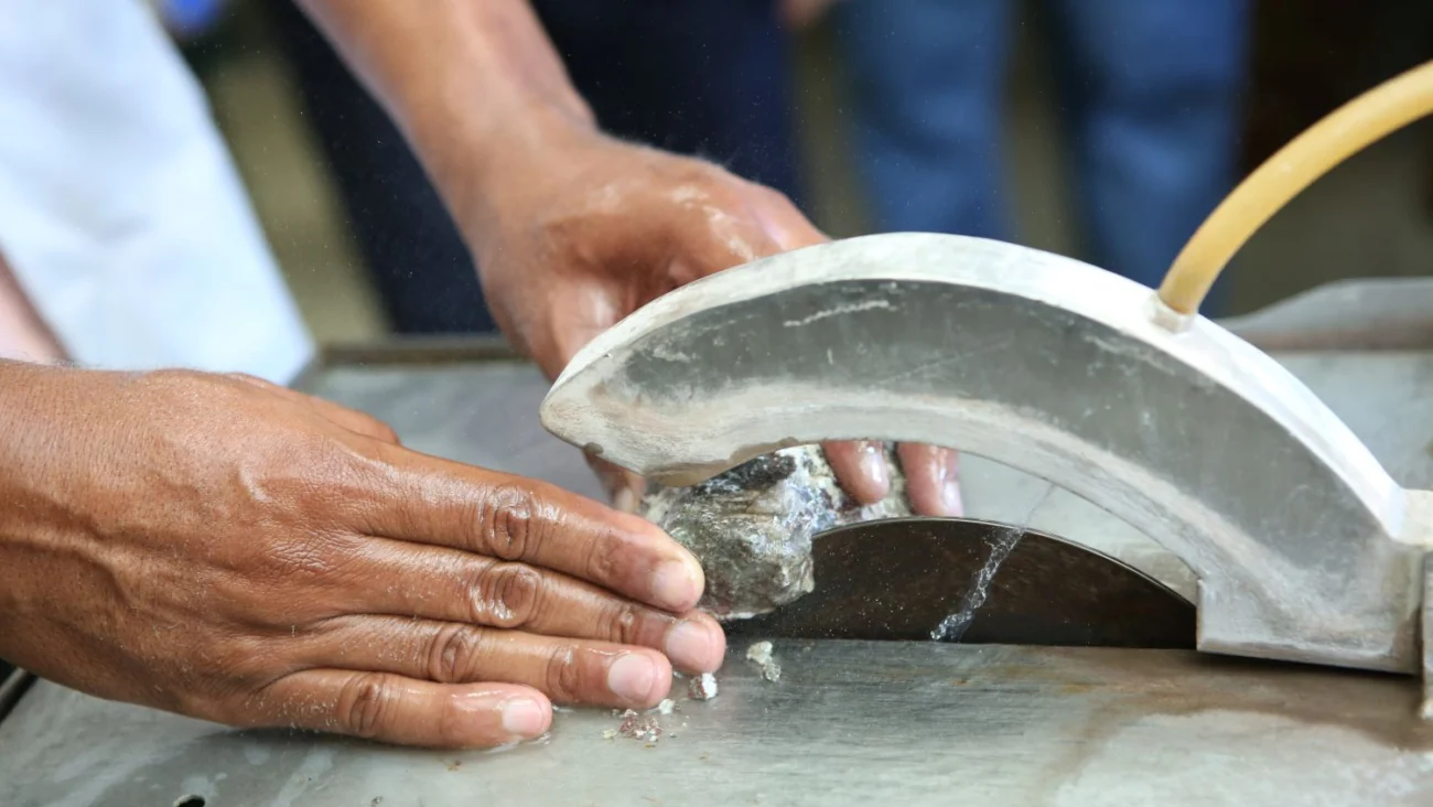 Artesano joyero examinando un dije de larimar genuino montado en plata sobre una mesa de trabajo.